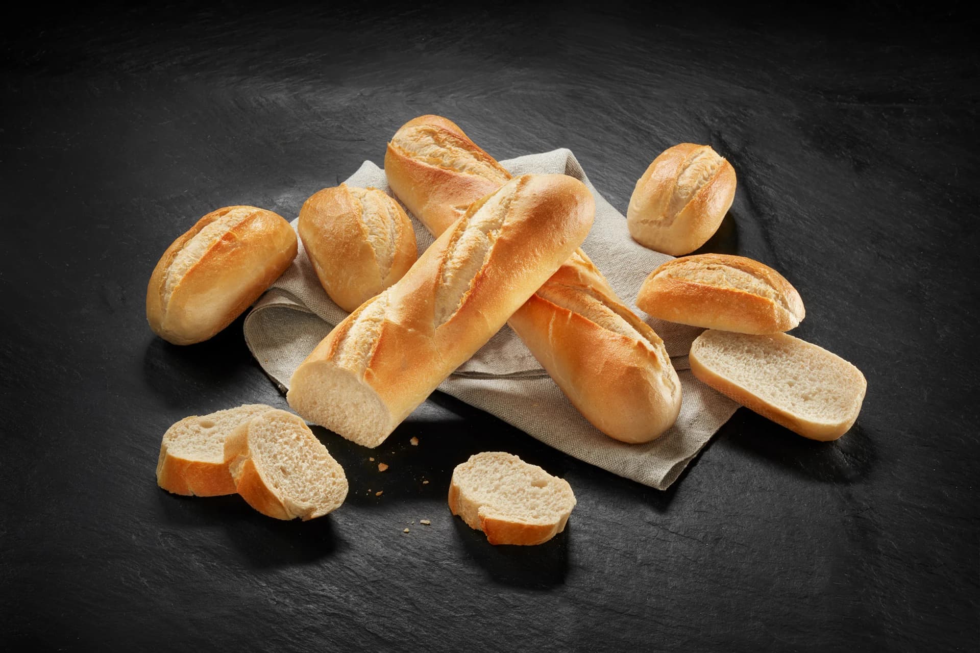 Bread rolls and baguettes on a dark surface